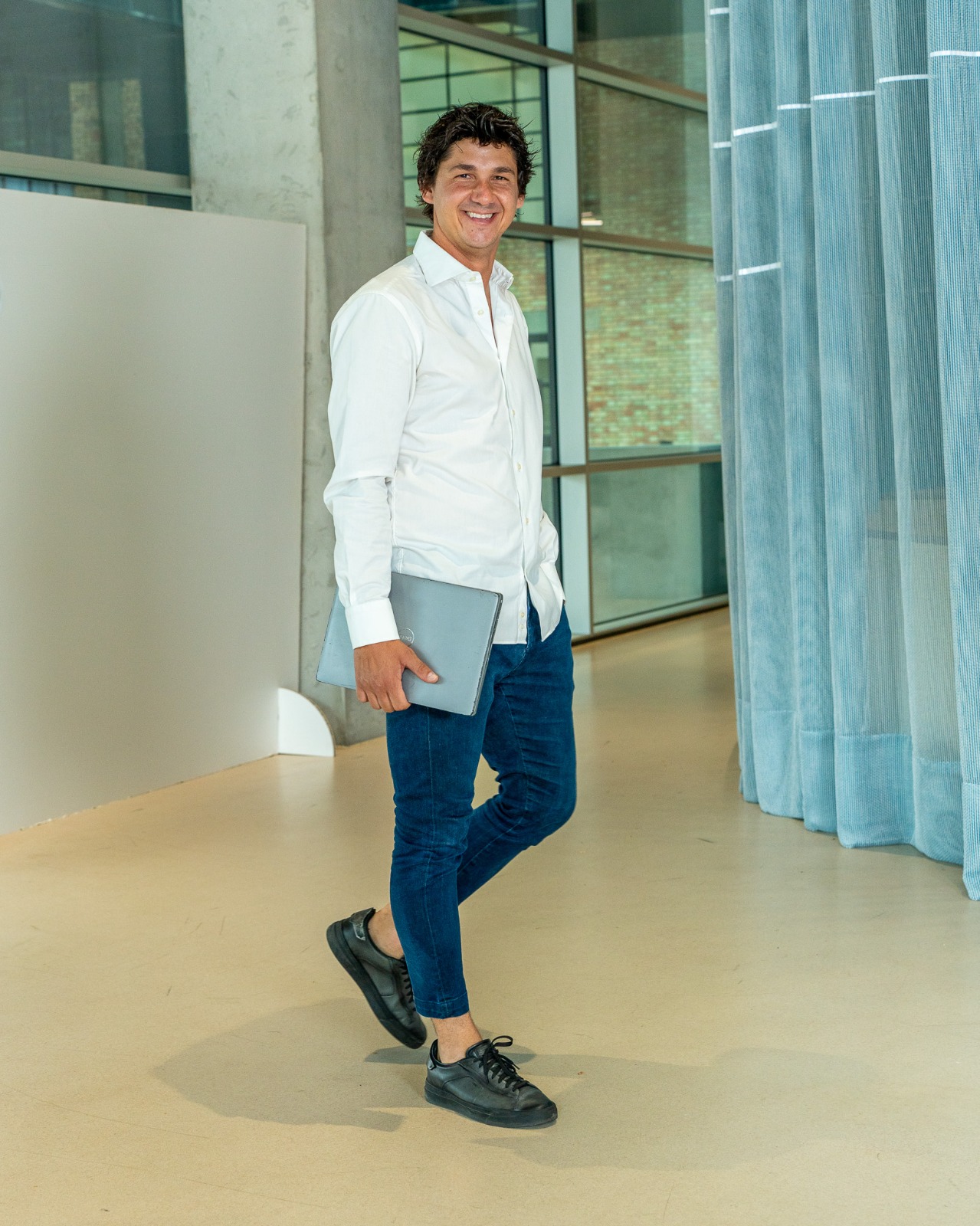 Mirza Cehaic, CEO di I-WIN, cammina sorridendo con il portatile sottobraccio